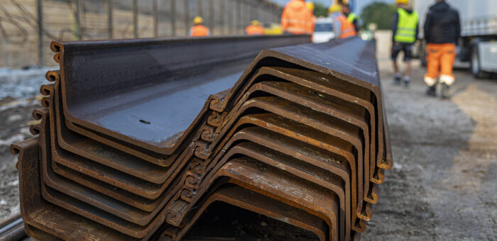 Das Foto zeigt Spundbohlen von Hoesch Spundwand, die auf einer Baustelle liegen und darauf warten, eingebaut zu werden.