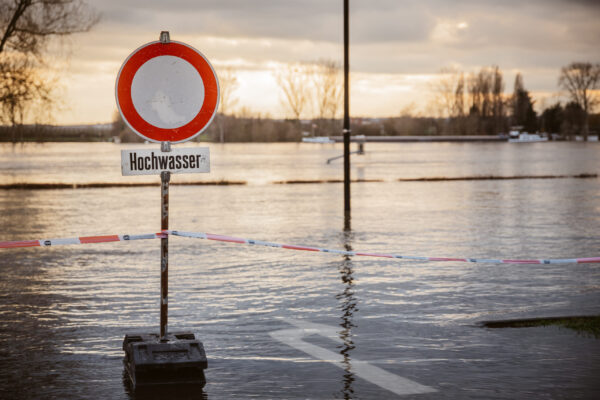 Schild Durchfahrt verboten mit dem Vermerk Hochwasser auf überfluteter Fahrbahn.
