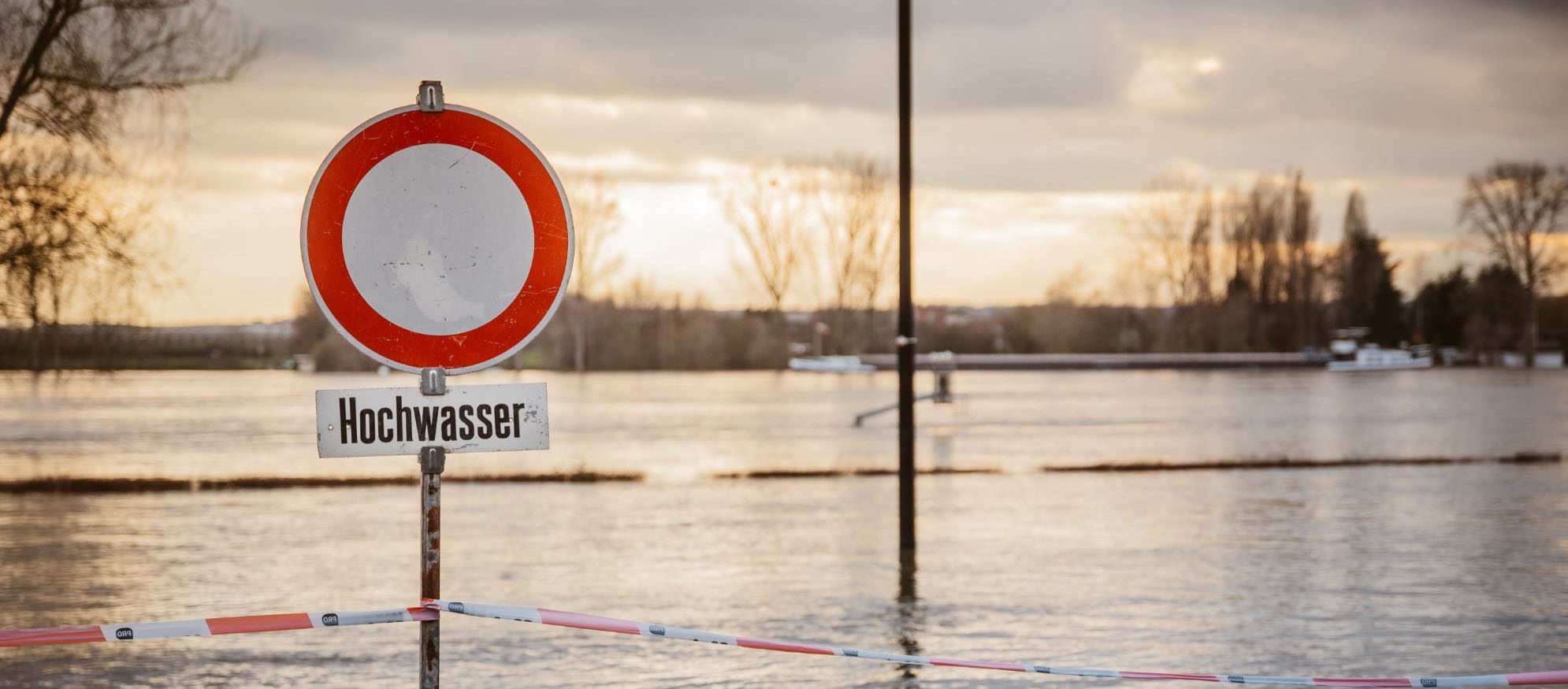 Schild Durchfahrt verboten mit dem Vermerk Hochwasser auf überfluteter Fahrbahn.